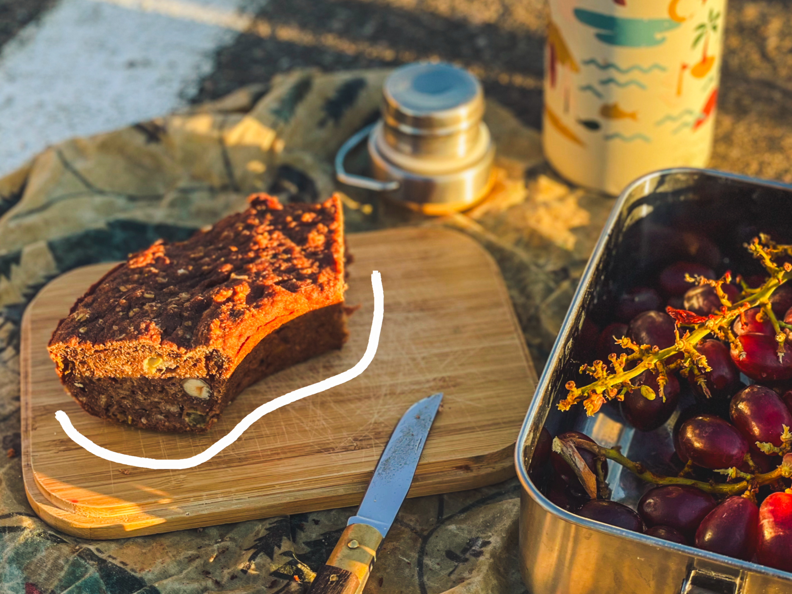 Bananenbrot aus dem Omnia auf Schneidebrett Deckel der Lunchbox von Roadtyping
