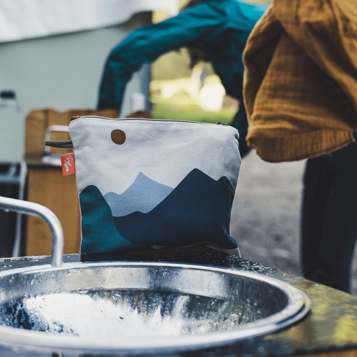 Kulturtasche mit blauem Bergmotiv am Spülbecken