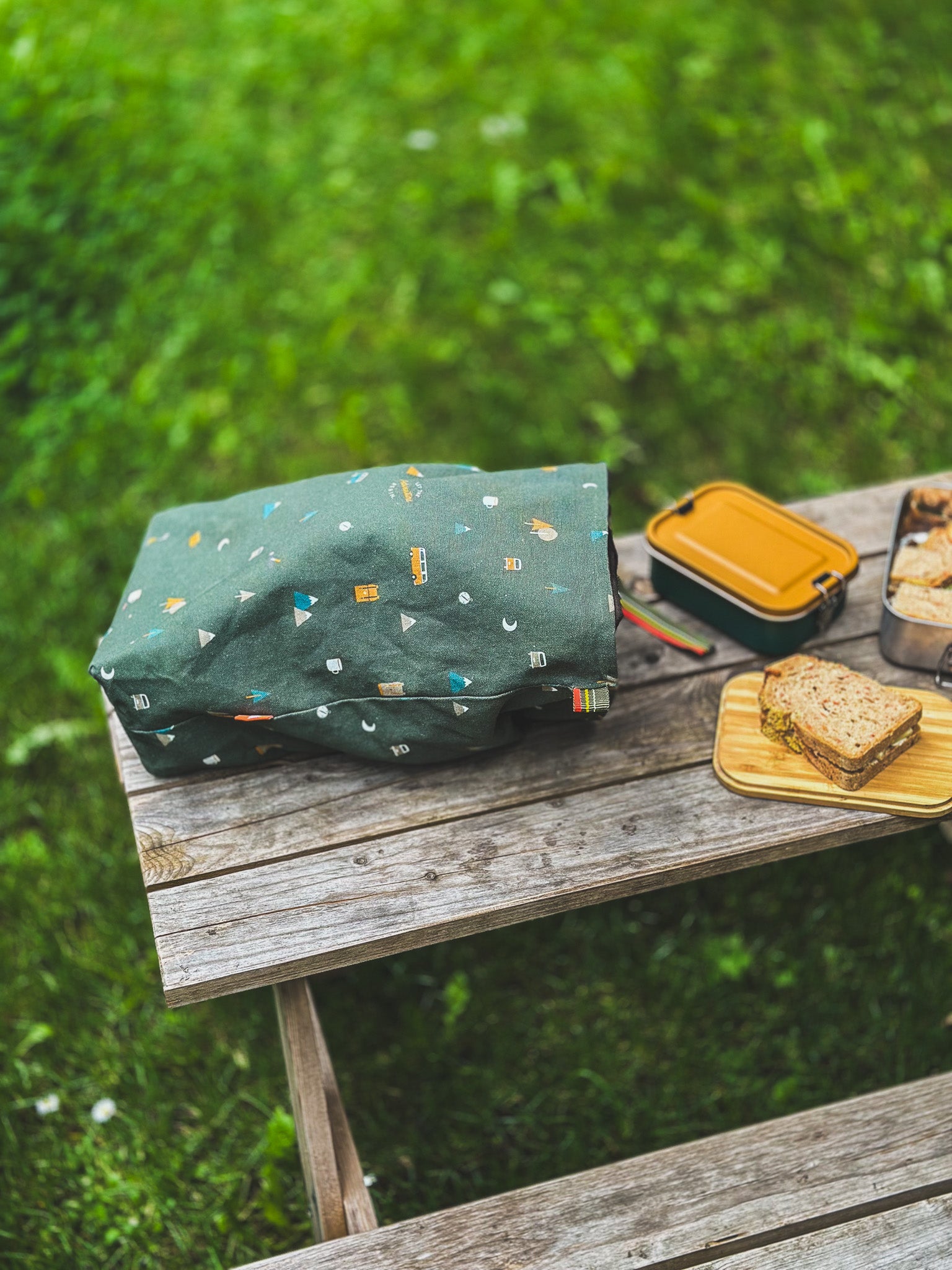 Grüner Lunchbag von Roadtyping mit Camping Accessoires liegt geöffnet auf Picknicktable