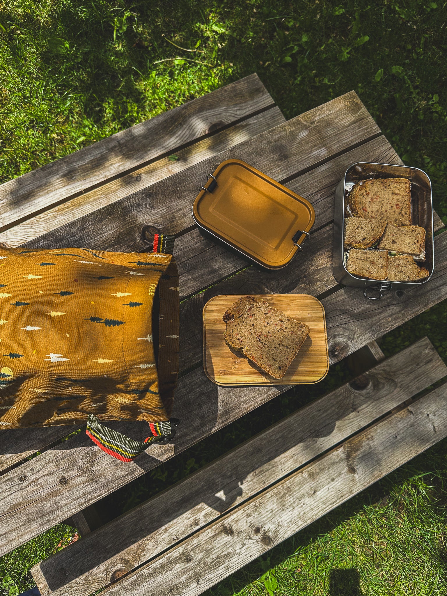 Braunen Lunchbag von Roadtyping liegt auf Picknicktable neben Brotdosen