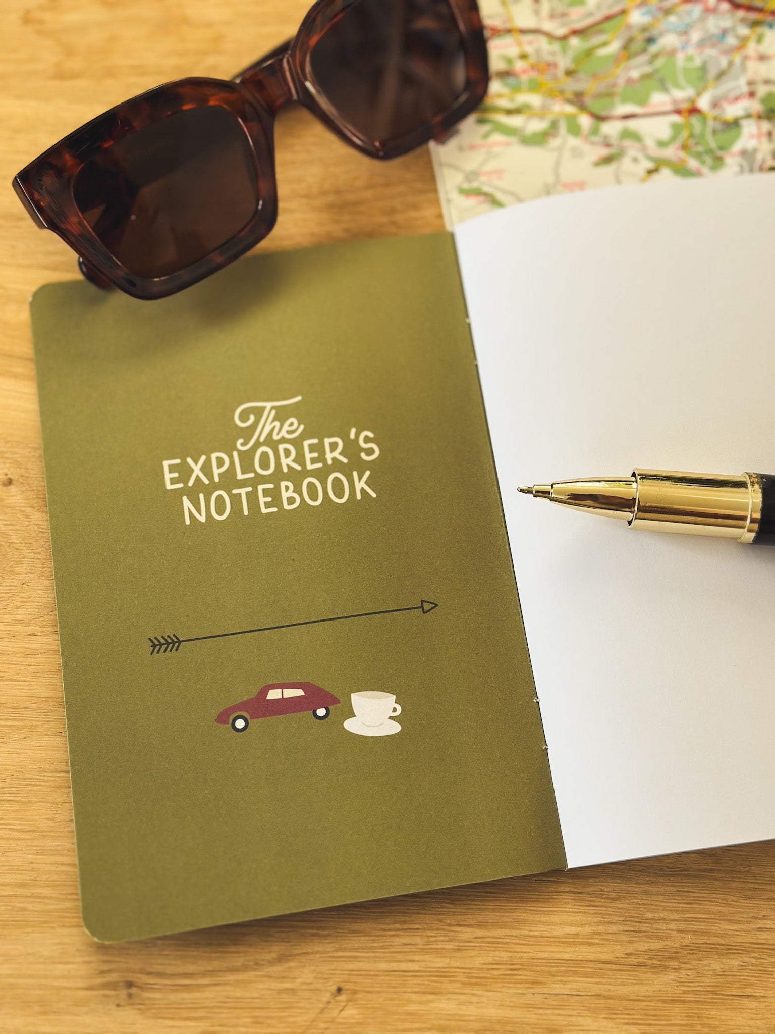 Reisetagebuch The Explorers Notebook Band 5 liegt offen auf einem Tisch neben Brille und Stadtplan