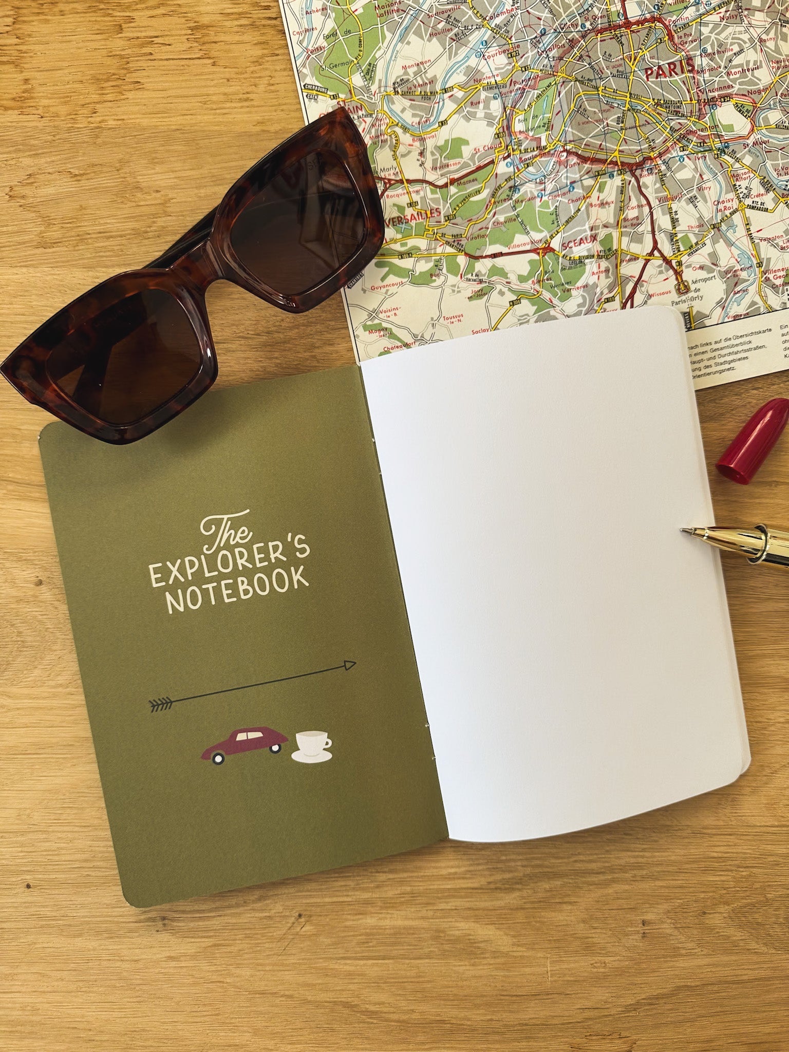 Reisetagebuch The Explorers Notebook Band 5 liegt offen auf einem Tisch neben Brille und Stadtplan
