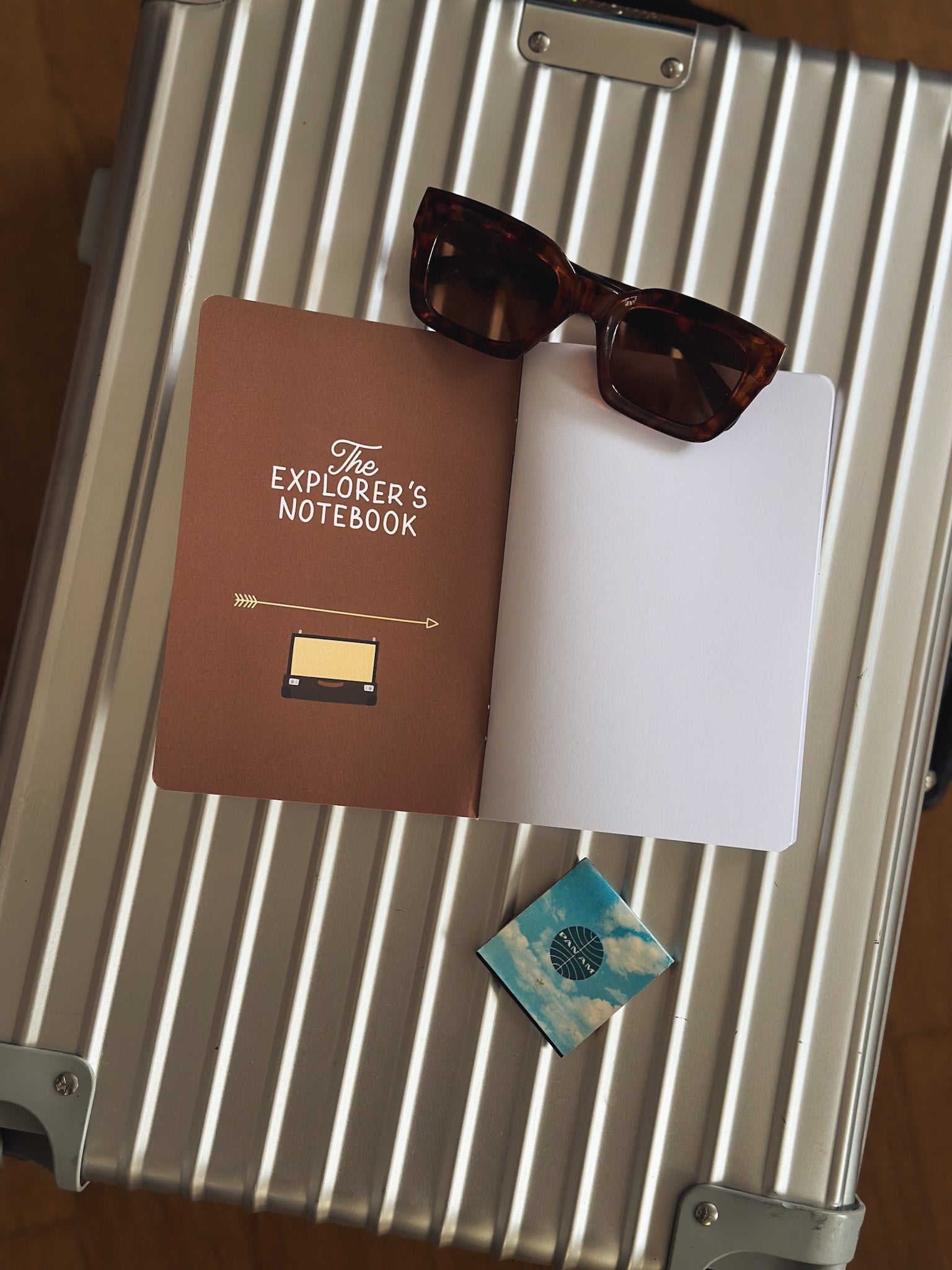 Reisetagebuch The Explorers Notebook Band 7 liegt offen auf einem Rimowa Koffern neben Streichhölzern von Panam